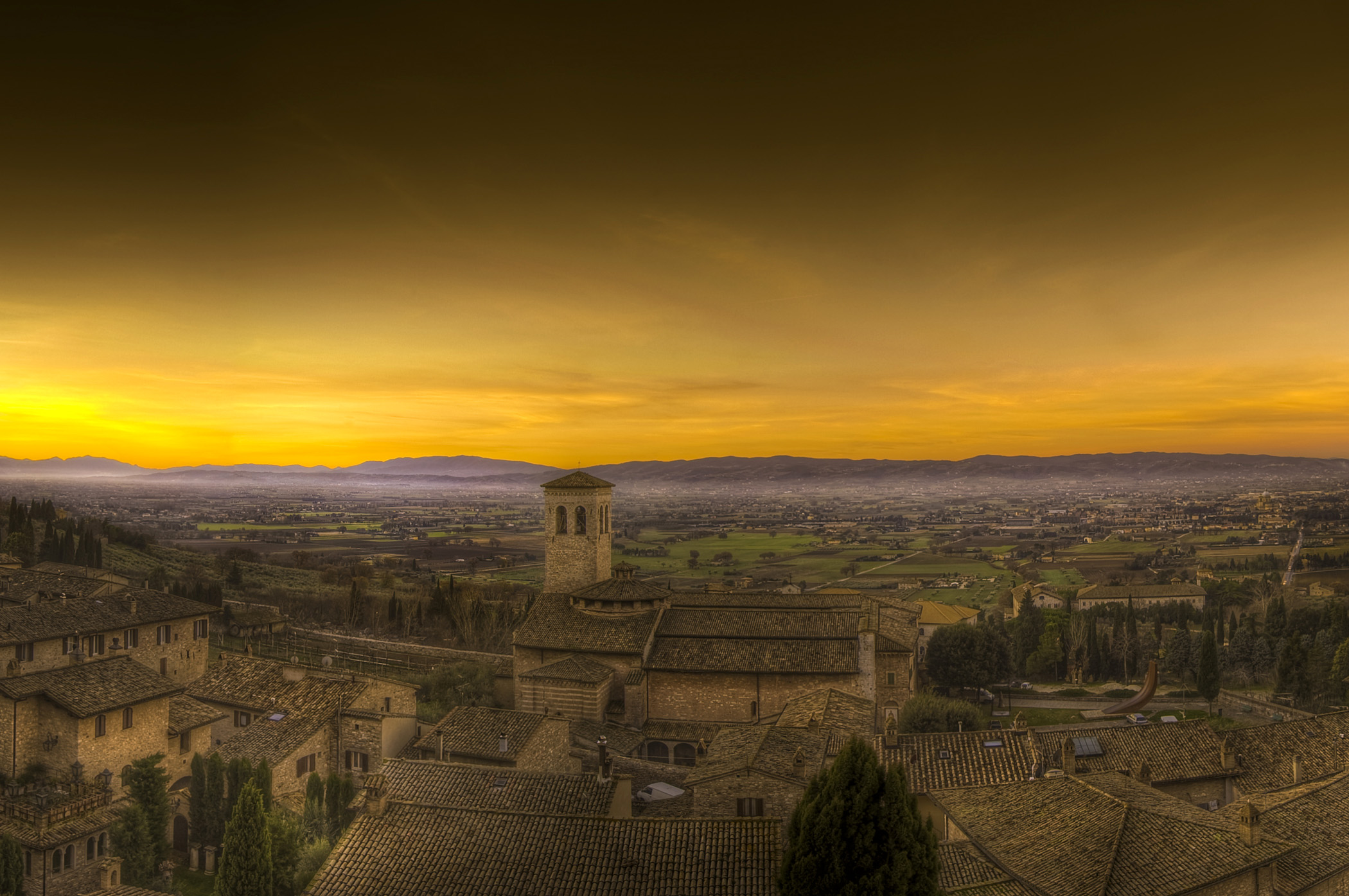 Dawn breaks across the valley below the ancient walled city of Assisi, Italy  on a December morning and mist lays upon the valley floor.